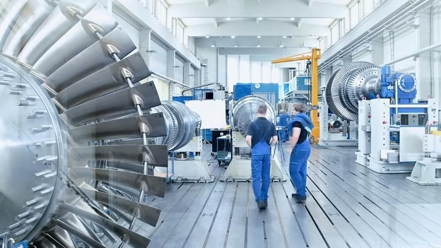 Hall with engineers, turbines and complex stainless steel machine components