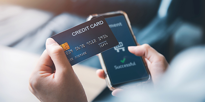 Eine Kreditkarte wird als Zahlungsmittel für eine Kaufabwicklung auf dem Smartphone verwendet